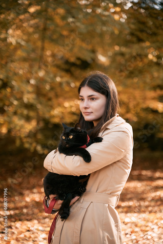 Beautiful girl is hugging her cat. Concept of weekend in the countryside area with your lovely pet. Brunette woman has great time with her black shorthair cat. © AlexGo