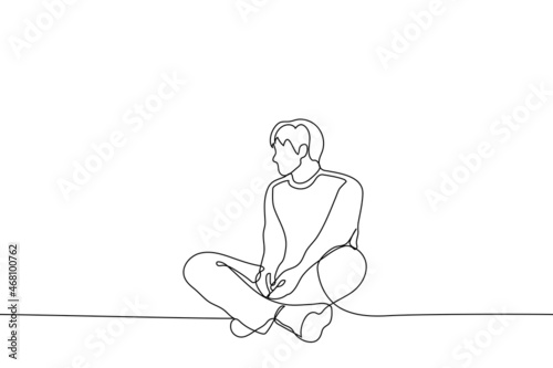 man sits on the floor with his legs bent at the knees his hands are freely lowered he turned his head to the side and listens and looks at someone