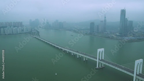 Hong Kong Zhuhai Macao bridge amazing construction with cars driving over ocean bay against foggy town. Contemporary seaside city infrastructure aerial view