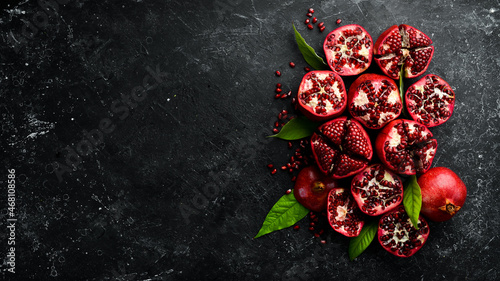 Ripe pomegranate fruit near leaf on dark wooden background. Free space for your text.