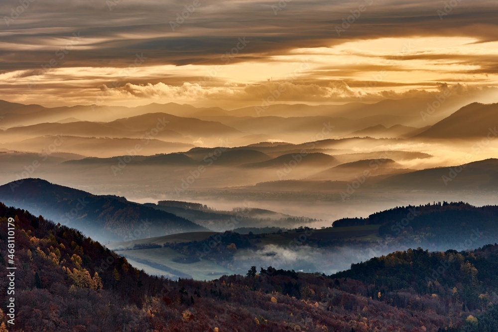 Obraz premium Autumn mountain misty landscape at dawn. View of the valley from Vrsatec hill, Slovakia. Morning soft light. with colored skies and clouds. Hills in the fog. 
