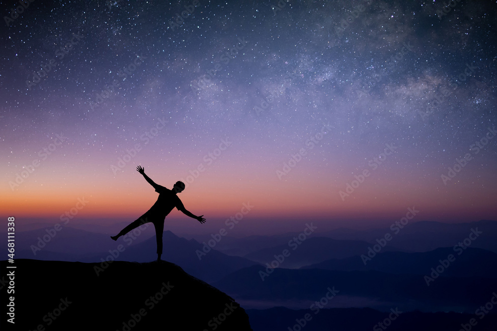 Silhouette of young traveler and backpacker standing and open arm looking the star and Milky Way alone on top of the mountain. He enjoyed traveling and was successful when he reached the summit.