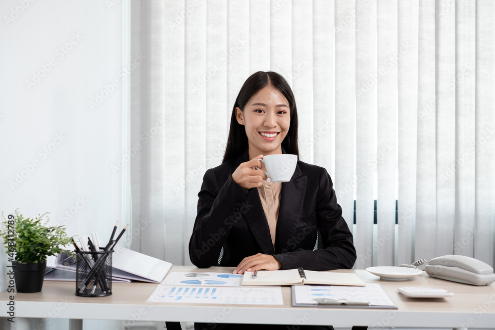 Asian businesswoman working on a laptop with a cheerful and happy smile while working at drink coffee the office Asian businesswoman working on a laptop with a cheerful and happy smile while working at drink coffee the office