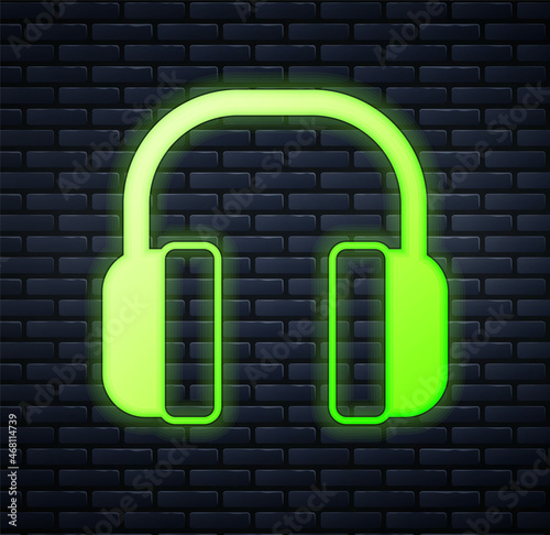 Glowing neon Noise canceling headphones icon isolated on brick wall background. Headphones for ear protection from noise. Vector