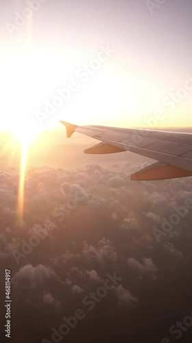 Wing of an airplane flying above the clouds in bright sunlight