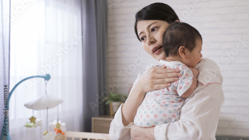 Tableau sur toile Taiwanese new mother is standing up from the bed and holding her baby properly while burping in the bedchamber at home
