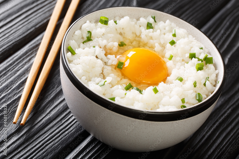 Tamago kake gohan is a simple Japanese dish made of raw Egg Over Rice close up in the bowl on the table. Horizontal Tamago kake gohan is a simple Japanese dish made of raw Egg Over Rice close up in the bowl on the table. Horizontal