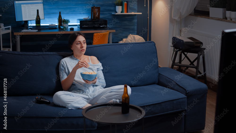 Focused young woman paying attention to horror film eating popcorn having shocked concentrated and amazed facial expression. Awestruck and wide-eyed lady reacting to astonishing moment on tv Focused young woman paying attention to horror film eating popcorn having shocked concentrated and amazed facial expression. Awestruck and wide-eyed lady reacting to astonishing moment on tv