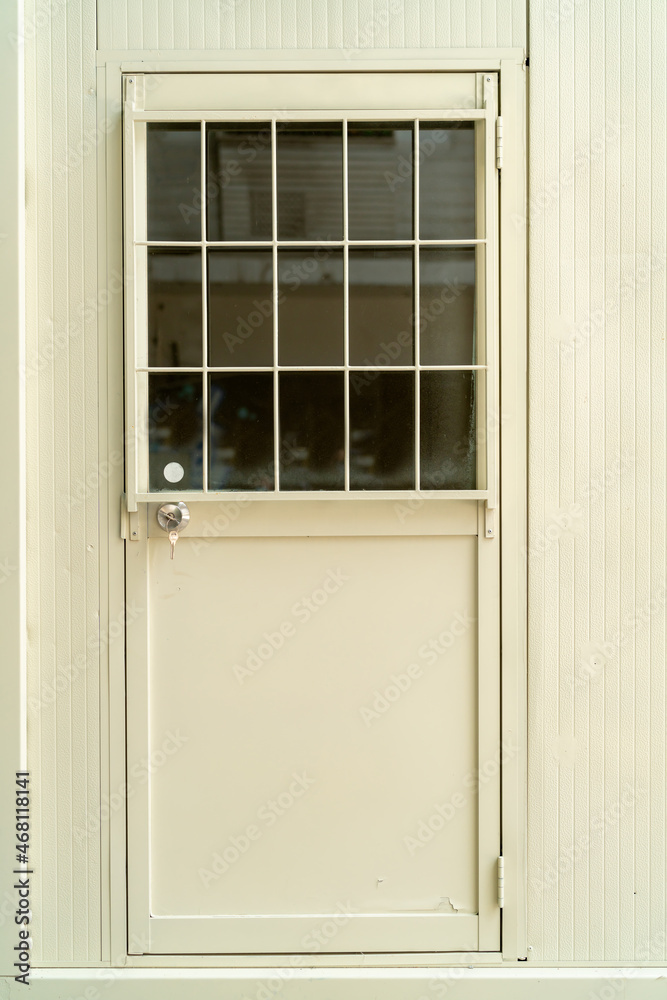 Fototapeta premium steel door The cream paint is off. The top of the door is glass and steel bars.