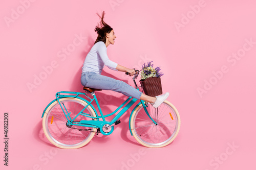 Fototapeta Naklejka Na Ścianę i Meble -  Photo of excited funky young lady dressed white jumper enjoying riding bicycle looking empty space isolated pink color background