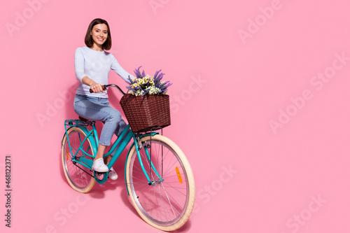 Photo of funky shiny young lady dressed white jumper enjoying riding bicycle empty space isolated pink color background
