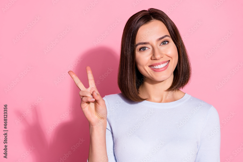 Photo of dreamy charming young lady dressed white jumper smiling showing v-sign empty space isolated pink color background Photo of dreamy charming young lady dressed white jumper smiling showing v-sign empty space isolated pink color background
