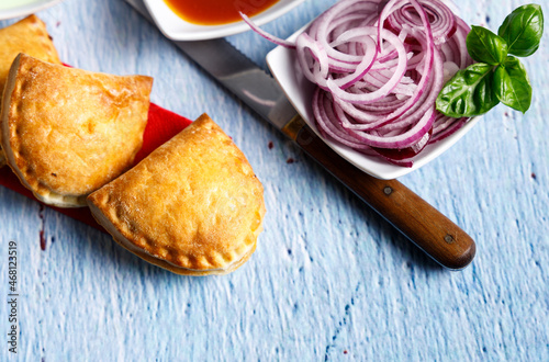 Homemade empanadas with sauces. South American street food. These delicious beef empanadas are mandatory to eat, they have a crunchy dough and an exquisite ground beef filling. photo