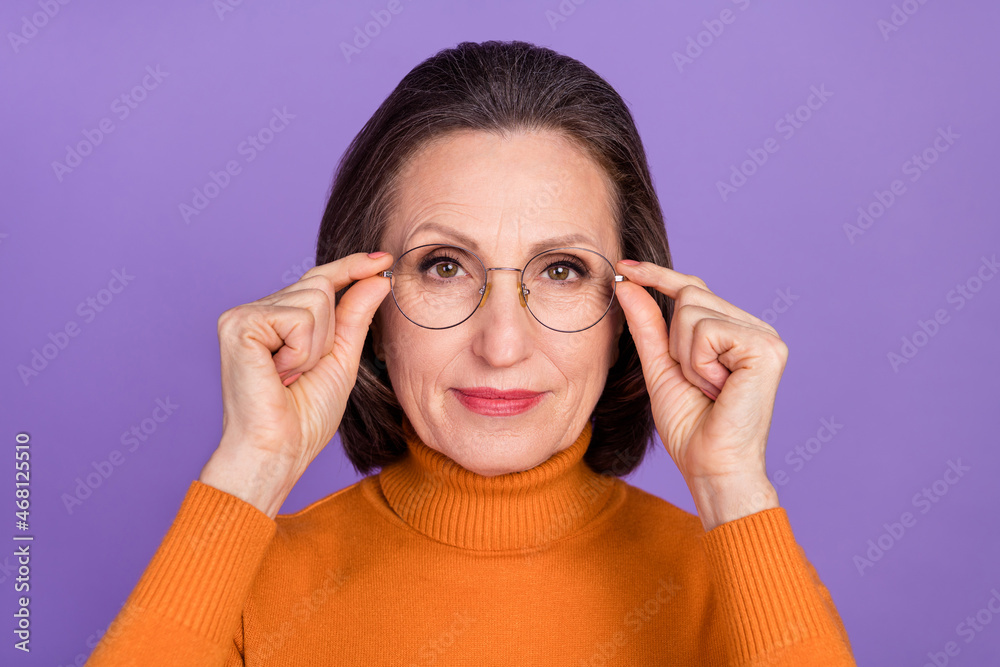 Photo of serious confident retired woman wear orange pullover arms spectacles isolated violet color background Photo of serious confident retired woman wear orange pullover arms spectacles isolated violet color background