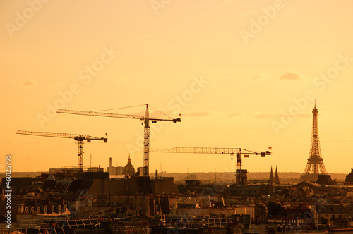 Photography Parisian cityscape with Eiffel tower and cranes at sunset