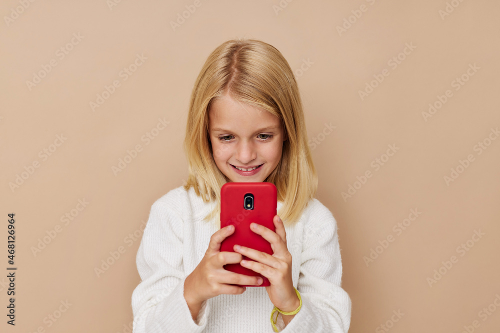 Positive little girl red phone in hand on a beige background