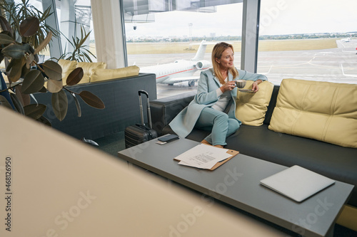 Fotografía Smiling airline passenger drinking coffee in airport lounge