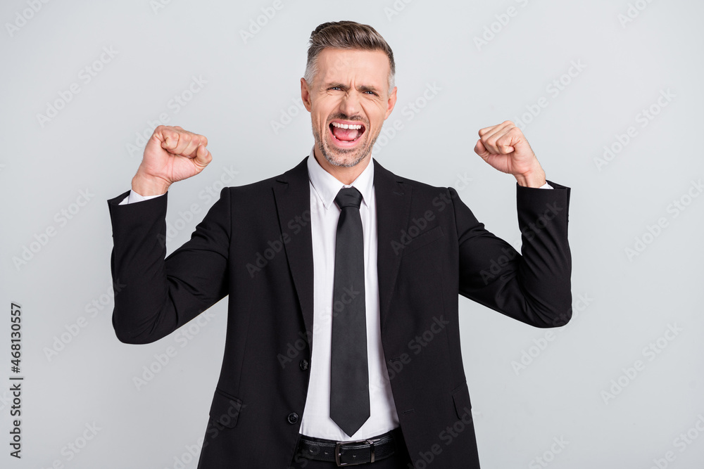 Photo of impressed lucky mature accountant dressed black suit rising fists successful achievement isolated grey color background Photo of impressed lucky mature accountant dressed black suit rising fists successful achievement isolated grey color background