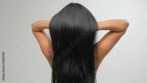 Brunette with luxurious hair on a white background in the studio. The girl pulls her hair. Hair care cosmetics. photo