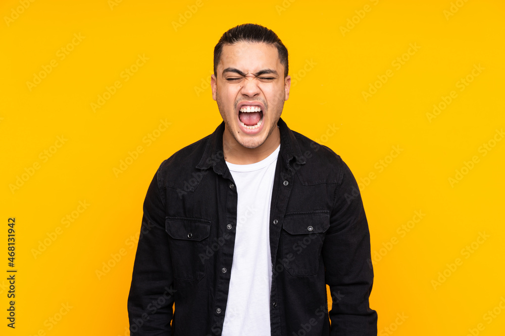 Fototapeta premium Asian handsome man isolated on yellow background pointing front with happy expression