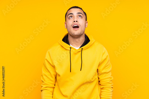 Asian handsome man isolated on yellow background shouting with mouth wide open