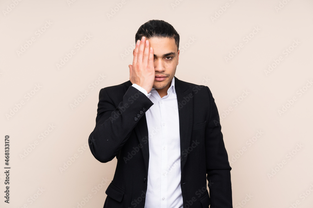 Asian business man isolated on beige background covering a eye by hand Asian business man isolated on beige background covering a eye by hand