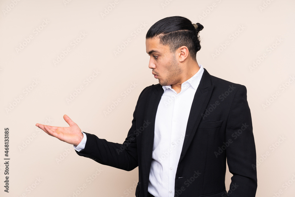 Asian business man isolated on beige background holding copyspace imaginary on the palm Asian business man isolated on beige background holding copyspace imaginary on the palm