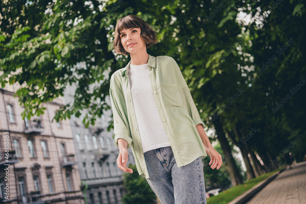 Fototapeta premium Photo of adorable dreamy young woman wear green shirt smiling walking outside city street