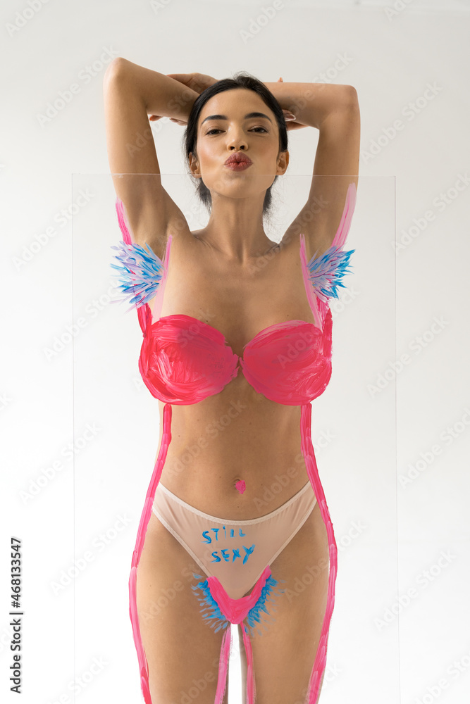 Woman sending air kiss to camera while posing over creative glass with unshaven armpits Woman sending air kiss to camera while posing over creative glass with unshaven armpits