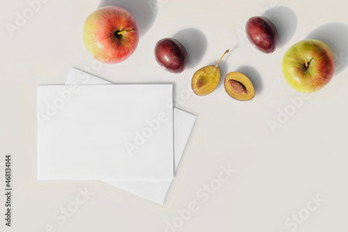 Mockup of blank white sheets of paper with fruits. Sunny summer day, long hard shadows. Flat lay.