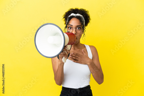 Young african american woman isolated on yellow background shouting through a megaphone with surprised expression