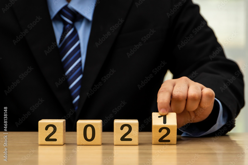 Obraz premium Businessman who looks forward confidently and turns calendar dates into years 2021, the concept of a man happily holding a wooden block with the number of years that change across.