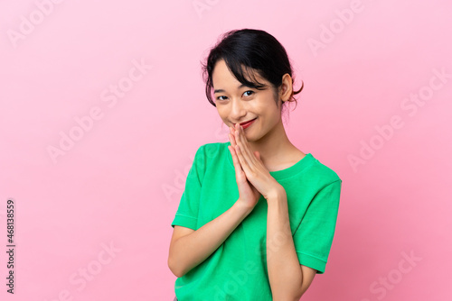 Young Vietnamese woman isolated on pink background keeps palm together. Person asks for something