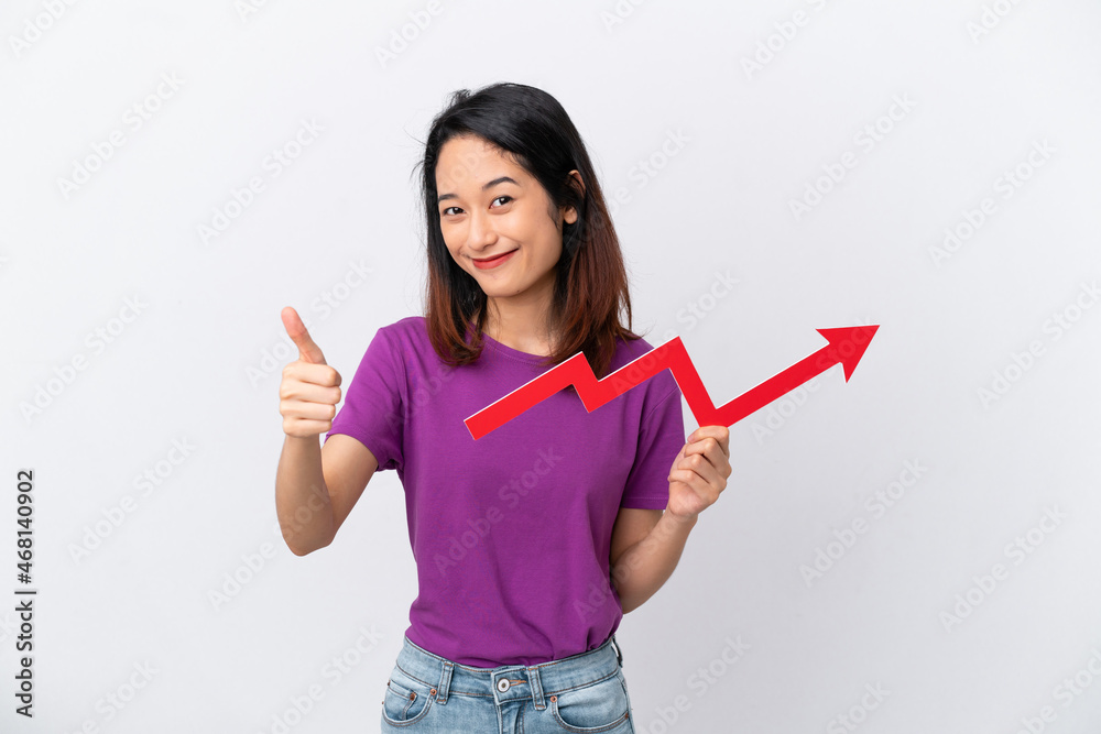 Young Vietnamese woman isolated on white background holding a catching a rising arrow with thumb up Young Vietnamese woman isolated on white background holding a catching a rising arrow with thumb up