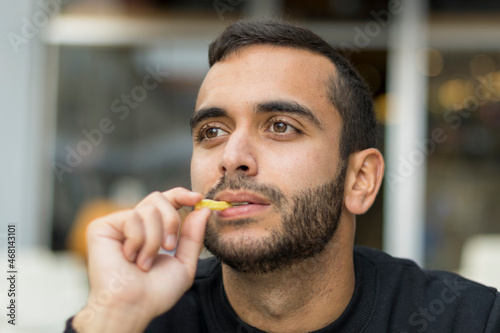 Primer plano de hombre jóven comiendo patatas fritas con diferentges y divertidas caras