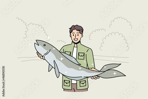 Smiling young fisherman hold big fish proud of good haul or hunt. Happy man in green costume satisfied with successful fishing. Hobby, fishery concept. Flat vector illustration, cartoon character. 