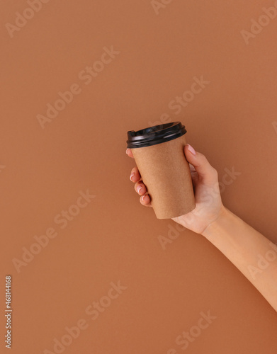 paper cup of coffee with place for logo in hand on beige background © Екатерина Клищевник