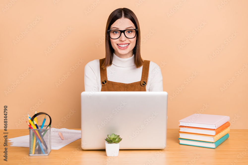 Portrait of attractive skilled cheery girl employee using laptop web programming isolated over beige color background Portrait of attractive skilled cheery girl employee using laptop web programming isolated over beige color background