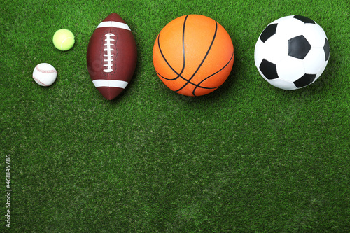 Set of different sport balls on green grass, flat lay. Space for text