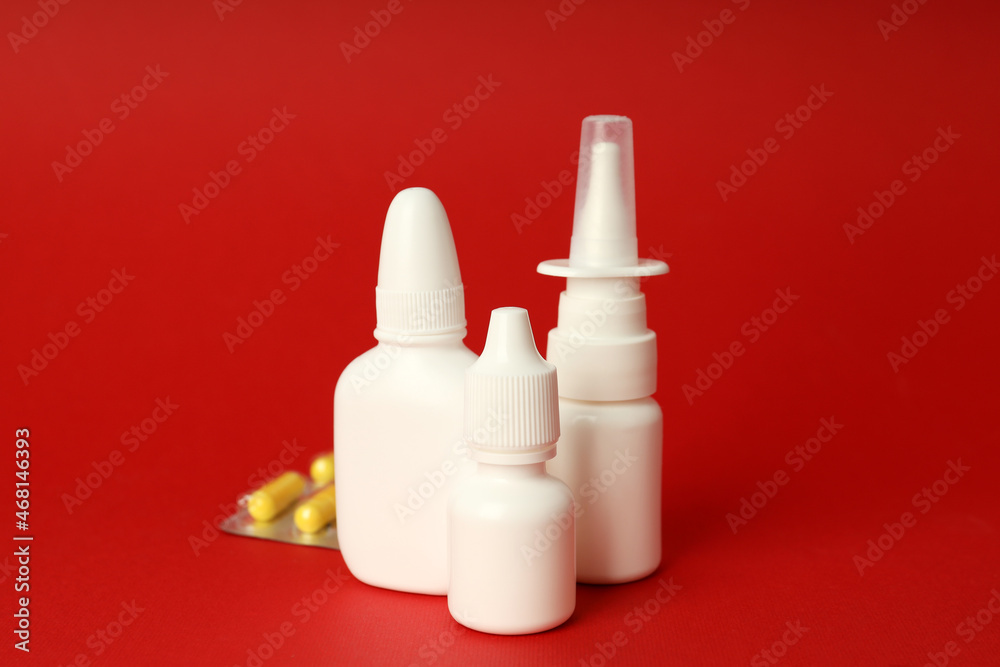 Blank bottles of nasal spray and pills on red background Blank bottles of nasal spray and pills on red background