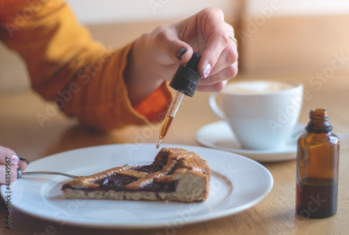 A girl in a yellow jacket is having breakfast in a cafe. Women's hands add THC and CBD oil to cherry pie. The concept of using medical marijuana.