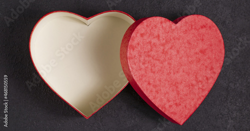 Gift box in the form of a red heart on a satin beige fabric. Concept for Valentine's Day. A gift for a loved one.