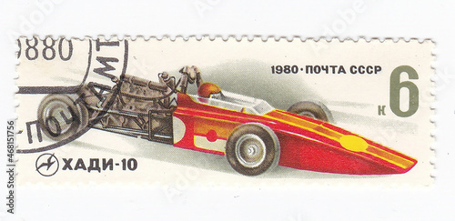Macro view of vintage postage stamp with a sport car. Perforated postage stamp country 1980 year. Used paper stamp  depicting auto sport transport 1980 year - Hadi car.  circa. Cool philatelic hobby. photo
