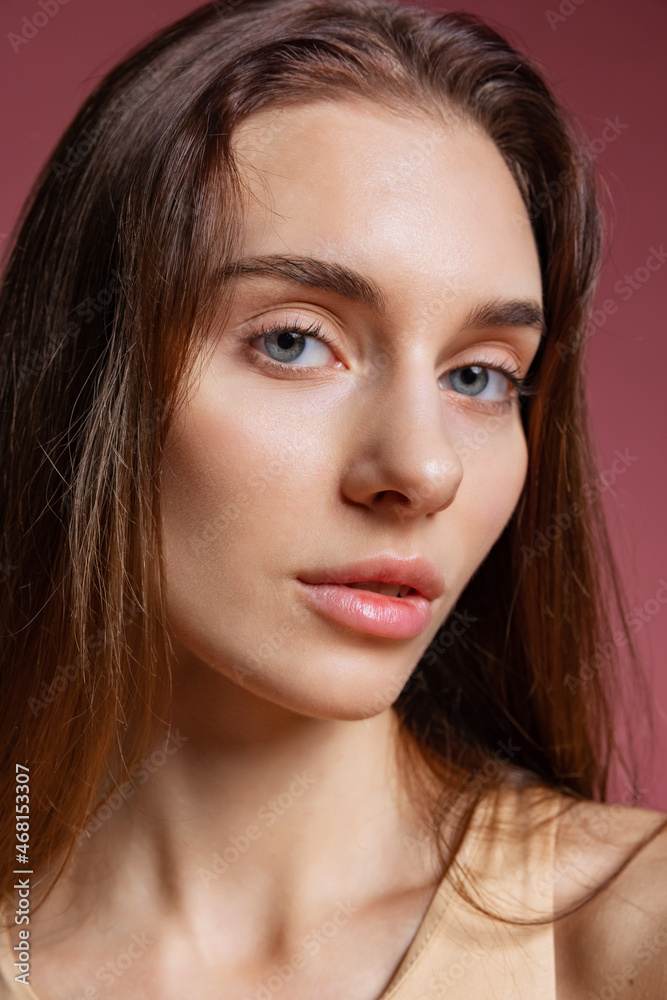 Close-up portrait of young beautiful girl without makeup isolated over dark pink studio background. Natural beauty concept. Close-up portrait of young beautiful girl without makeup isolated over dark pink studio background. Natural beauty concept.
