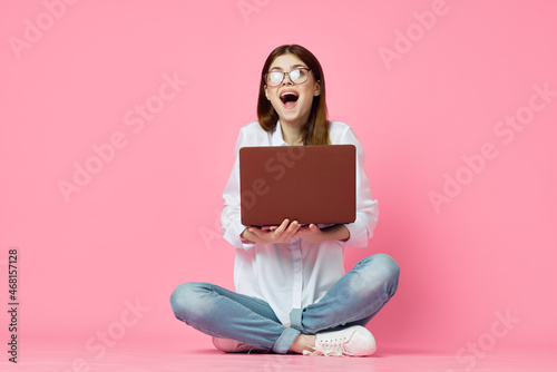 woman sitting on floor with laptop shopping entertainment pink background