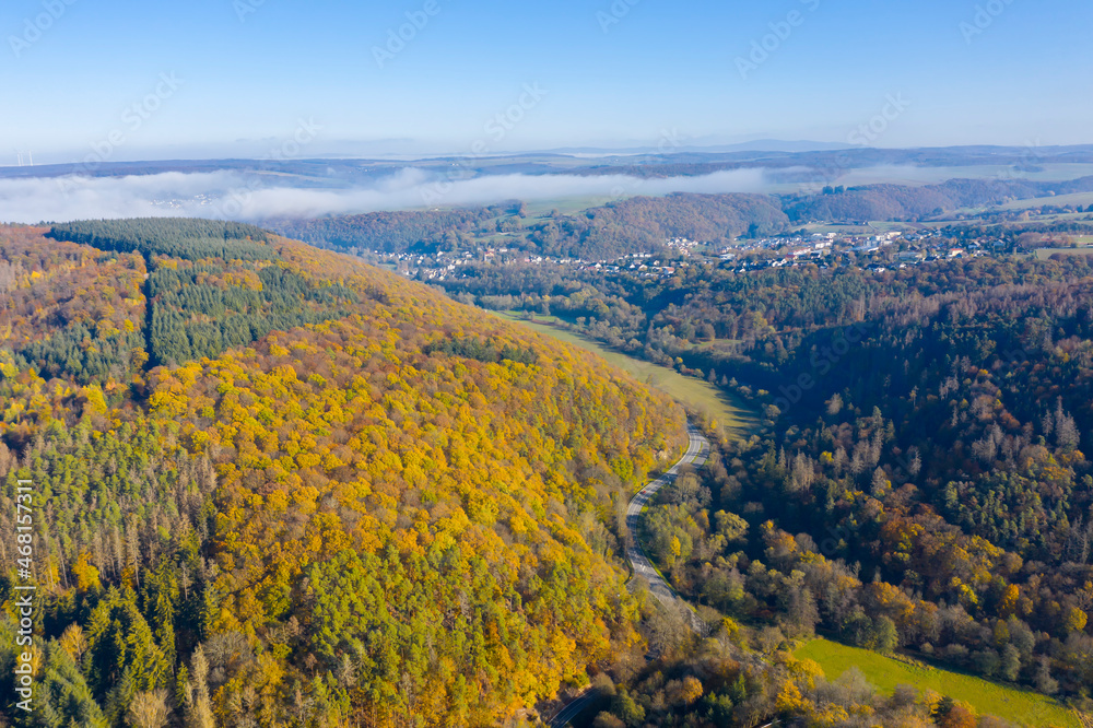 Bird's-eye view of the autumn-colored Aar valley with light morning fog 
