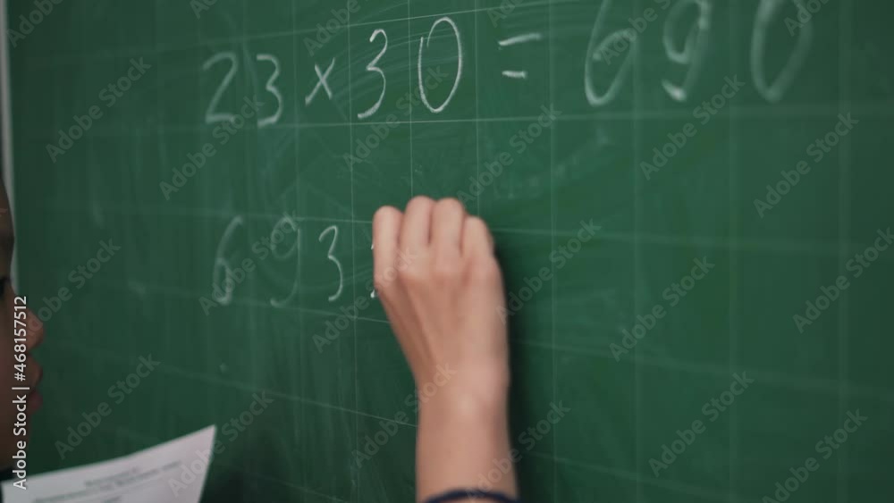 Close-up view of Asian girl writes a math example on a blackboard Close-up view of Asian girl writes a math example on a blackboard