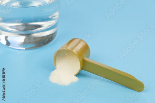 Hydrolyzed Marine Collagen Powder in measuring spoon, glass of water on a blue background. Collagen is support for healthy nails, joints, bones. Concept: healthy lifestyle, taking care of your health