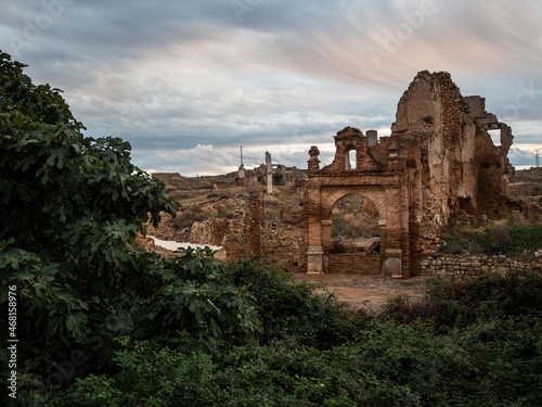 ruinas del pueblo viejo de Belchite con el cielo nublado y árboles en primer plano