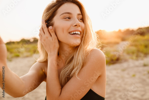 Young blonde woman smiling while taking selfie photo